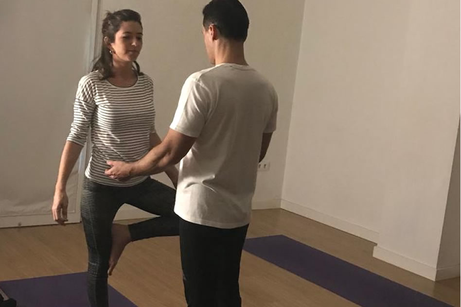 Profesor ajustando una asana adecuadamente en una sesión de yoga matutina